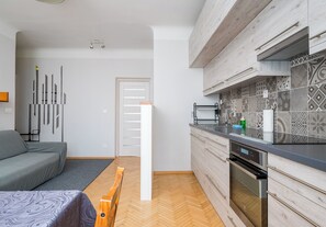 Eine moderne Küche mit Einbauofen, ein Essbereich mit einer Bank und ein Wohnzimmer mit einer Couch.