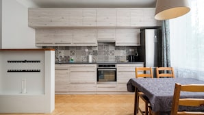 Eine moderne Küche mit Holzausstattung, einem Einbauofen und einem Essbereich mit Tisch und Stühlen.