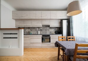 Eine moderne Küche mit Holzausstattung, einem Einbauofen und einem Essbereich mit Tisch und Stühlen.