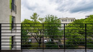 A building with a balcony, a metal fence, and trees in the background.
