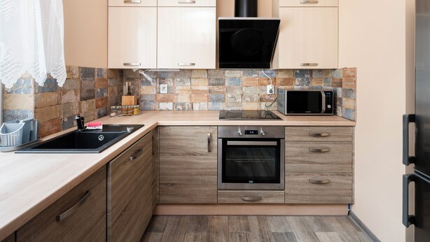 A compact kitchen with wooden cabinets, a built-in microwave, a stove, and a dishwasher.