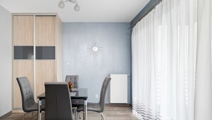 A modern dining area with a table, chairs, a wall clock, and a radiator.