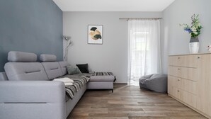 A modern living room with a grey sofa, a wooden cabinet, and a herringbone-patterned floor.