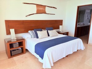 A bedroom with a large bed, wooden headboard, bedside tables, and a hanging wall decoration. - ON THE BEACH - Stunning 5th Floor Views - Boutique 3BR/4BA (Bucerías)
