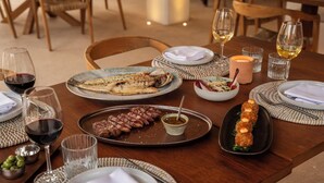 A dining table set with plates of food, glasses of wine, and candles. - Las Dunas Apt (Formentera)