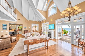 A spacious living room with a fireplace, a dining area, and a view of the ocean. - PRIVATE BEACH / Heated Pool / volleyball court/ Orchid Beach Key (Islamorada)