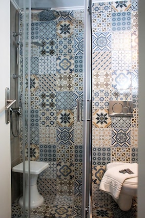 A bathroom with a shower enclosure, a toilet, and a sink. - Balito (Chania)