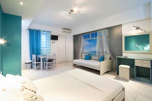 A bedroom with a bed, a desk, a chair, a window with a view, a TV, and a bathroom. - Balito (Chania)