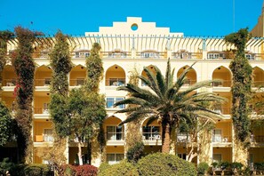 Un hotel de varios pisos con balcones arqueados, techo plano y un elemento circular central.