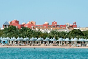 Un resort con piscina, sombrillas de playa y palmeras.