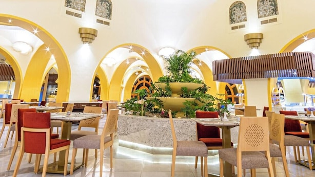 A spacious dining area with a central fountain, yellow arches, and a circular ceiling design. - Grand Resort (Hurghada)