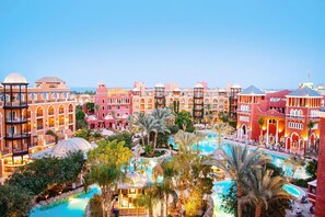 A resort with multiple buildings, a central swimming pool, and palm trees. - Grand Resort (Hurghada)