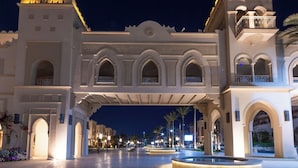 A grand entrance with arches and a covered walkway, palm trees, and a fountain. - Grand Resort (Hurghada)