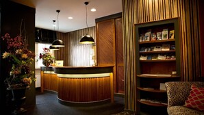 A reception area with a wooden reception desk, pendant lights, a bookshelf, and a patterned rug. - Karpfen (Eberbach)