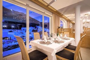 A dining table set for four with a view of a snowy landscape through large windows. - Grones (Ortisei)