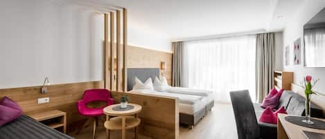 Moderni hotellihuone, jossa on sänky, työpöytä, tuoli, pieni pöytä ja sohva.