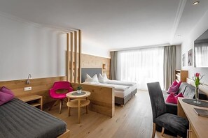 Quarto de hotel com cama, escrivaninha, cadeira, mesa pequena e sofá.