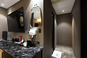 Een moderne badkamer met een marmeren aanrecht, een haardroger, een spiegel en een douche.