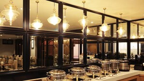 Dispositiu de buffet amb diverses estacions de servei, un mirall que reflecteix la sala i lluminàries de cristall penjants.