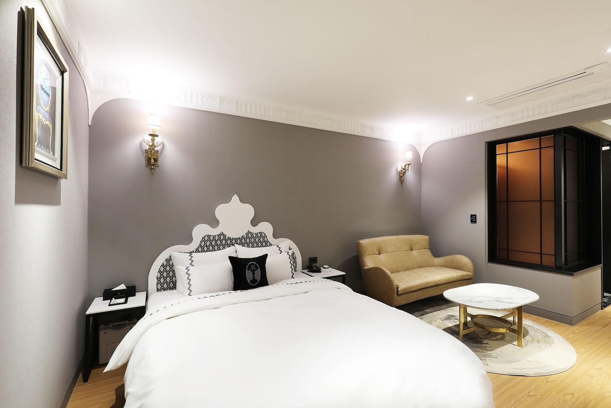 A modern bedroom with a bed, a chair, a small table, and a window.