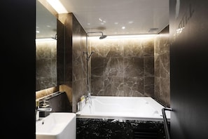 A modern bathroom with a bathtub, a sink, and a shower. - M (Paju)