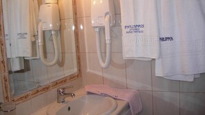 A bathroom with a sink, mirror, towel rack, and a hairdryer. - Philippos Studios & Apartments (Kos)