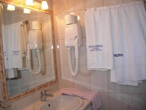 A bathroom with a sink, mirror, towel rack, and a hairdryer. - Philippos Studios & Apartments (Kos)