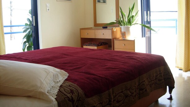 A hotel room with a bed, a dresser, a mirror, and a potted plant. - Philippos Studios & Apartments (Kos)