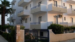 A multi-story residential building with balconies, air conditioning units, and a gated entrance. - Philippos Studios & Apartments (Kos)