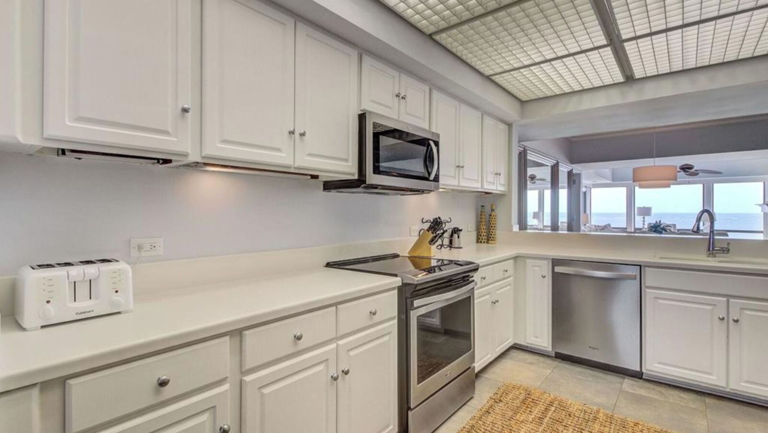 A modern kitchen with white cabinetry, a built-in microwave, a stove, and a large window offering a view.