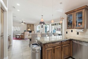 Eine moderne Küche mit Granit-Arbeitsplatten, Holzschränken und Pendelleuchten.