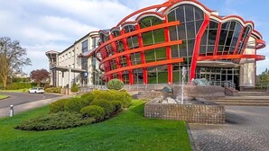 A modern building with a unique curved facade, a fountain, and well-maintained landscaping. - Land-gut-hotel Olympic (Wronki)
