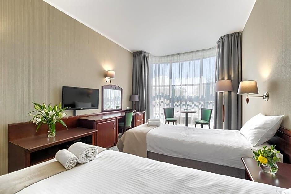 Une chambre d’hôtel avec deux lits, un bureau, une télévision et une vue sur la ville.