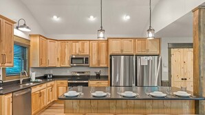 Cocina moderna con armarios de madera, electrodomésticos de acero inoxidable y una isla central con taburetes.