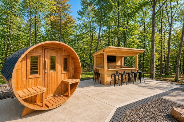 A wooden cabin with a circular interior and a separate wooden structure with a bar and seating area.