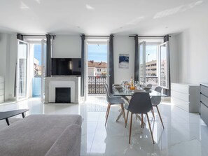 Un salon moderne doté d’une cheminée, d’un coin repas et de grandes fenêtres.