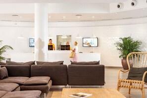 A modern lobby with a reception desk, seating area, and a television screen. - Sunwing Resort Fanabe (Adeje)