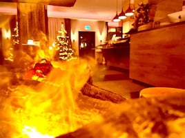 Un vestíbulo de hotel con un árbol de Navidad, un mostrador de recepción y una chimenea.