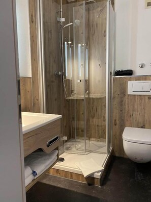Un baño con cabina de ducha, lavabo e inodoro.
