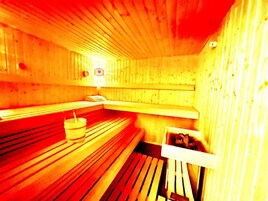 Una sauna con bancos de madera y un cubo pequeño.