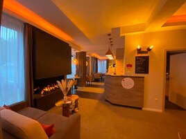 Un hall de hotel con un sofá, una chimenea, un mostrador de recepción y una pantalla grande.