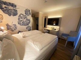 Una habitación de hotel con una cama grande, un escritorio con espejo y una silla.