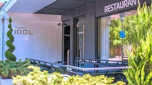 A modern hotel exterior with a restaurant sign, a reception area, and a glass entrance. - Hotel Idol (Targovishte)
