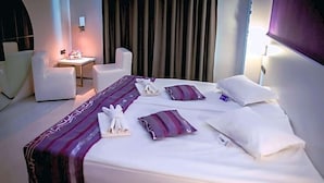 A hotel room with a bed, two white chairs, a small table, and a curtain backdrop. - Hotel Idol (Targovishte)
