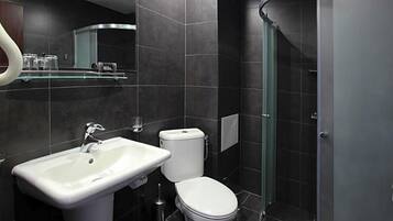 Un baño moderno con lavamanos, inodoro y cabina de ducha de vidrio.
