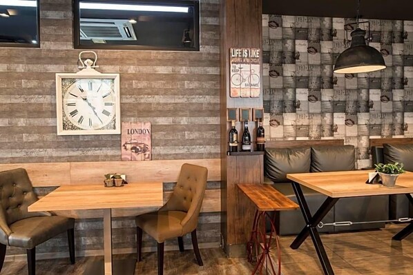 A modern interior with wooden walls, a clock, a bicycle-themed sign, and leather seating. - Hotel Idol (Targovishte)