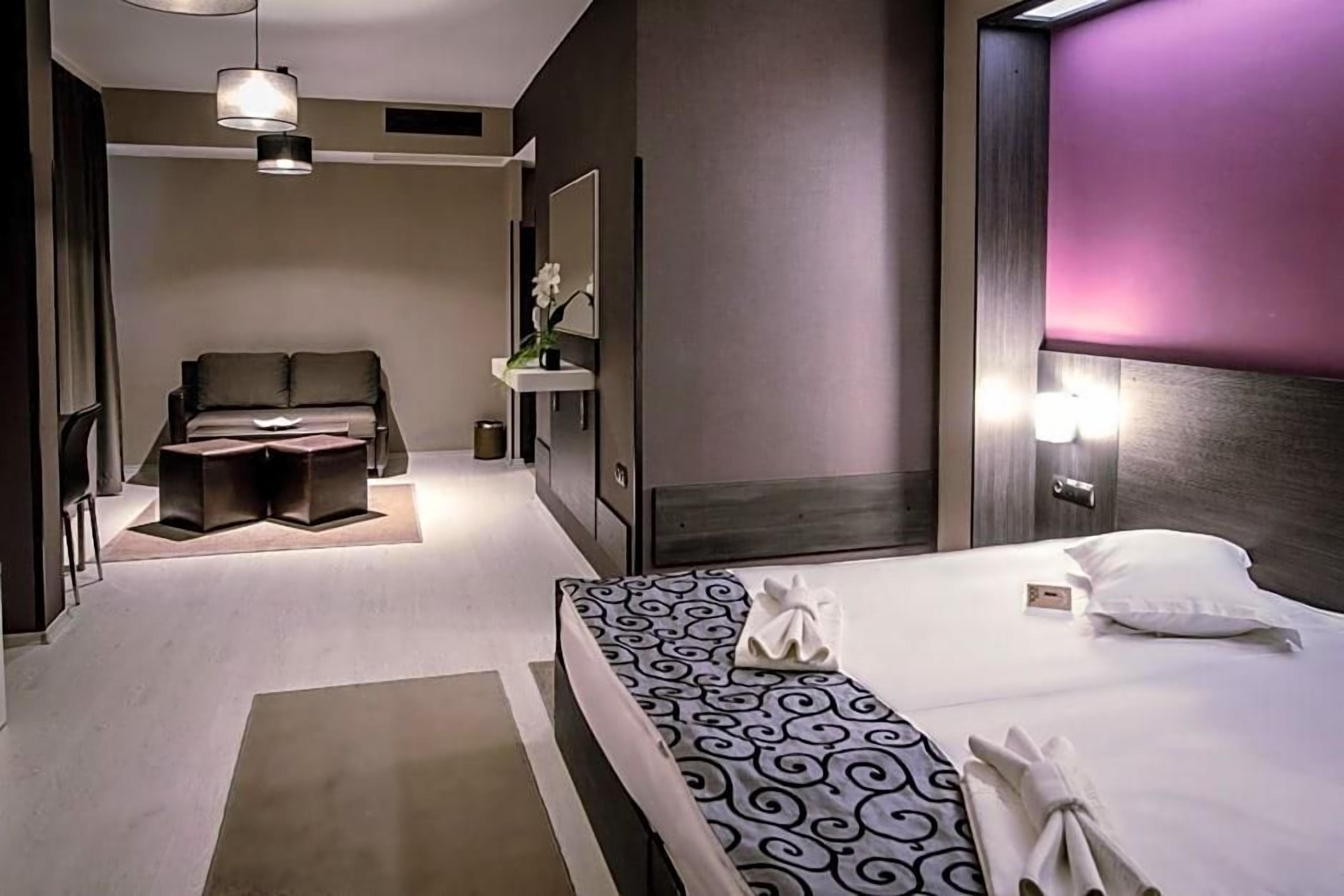 Una habitación de hotel moderna con una cama grande, una mesita de noche, un escritorio y una silla.