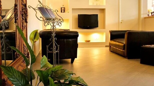 A living room with a sofa, a TV, and a decorative mirror. - Villagio La Darsena (Scarlino)