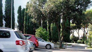 A parking lot with cars and trees. - Villagio La Darsena (Scarlino)