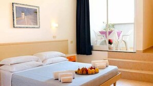 A hotel room with a bed, a breakfast tray, a painting, and a view of the outside. - Villagio La Darsena (Scarlino)
